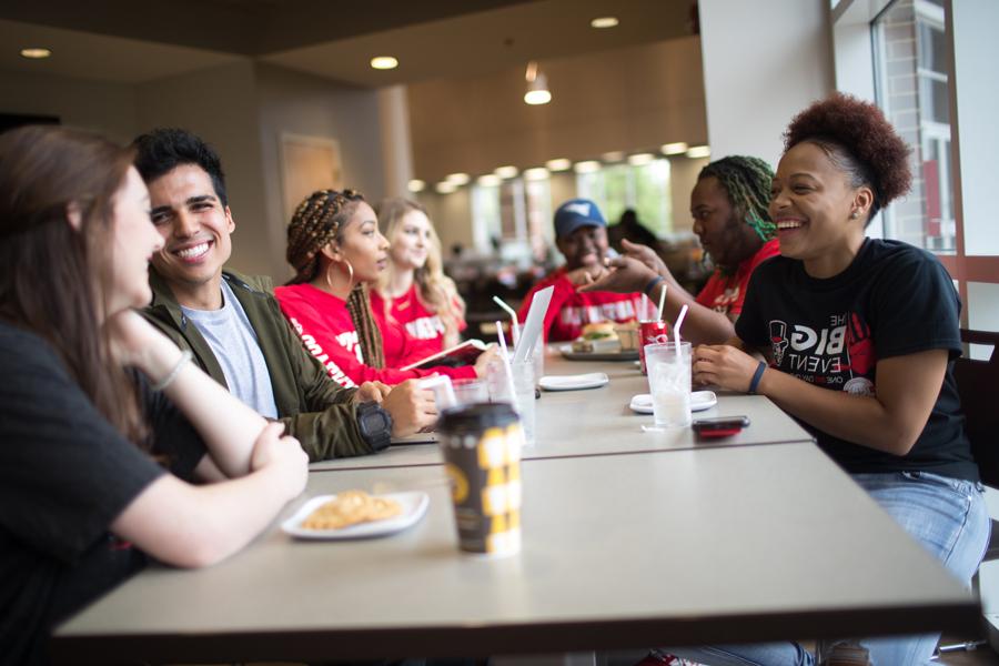 Students sitting around the table having lunch.